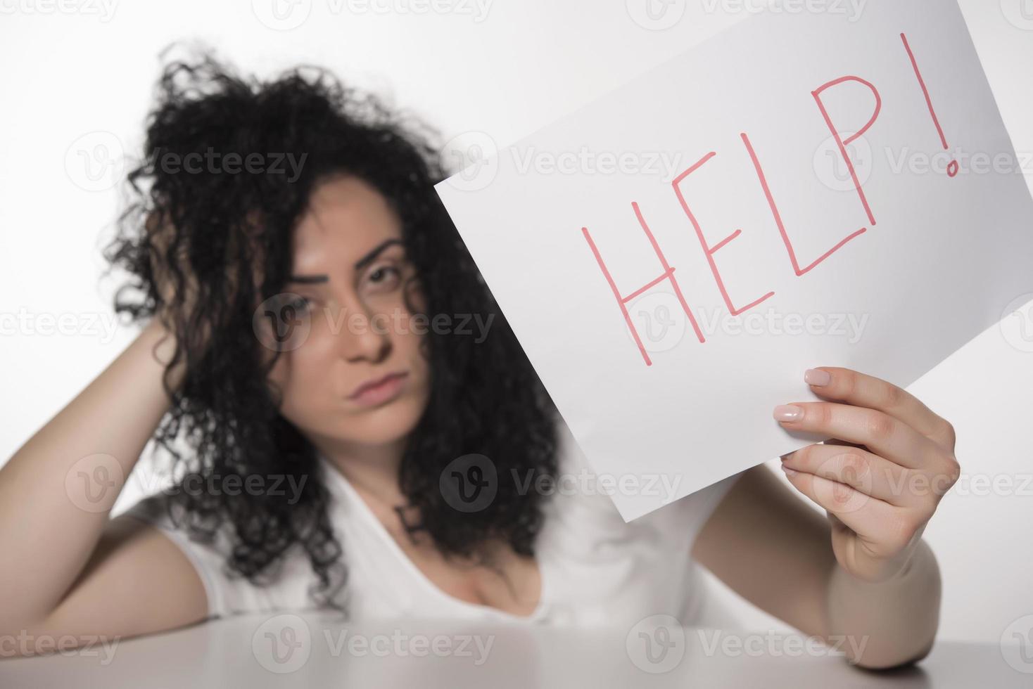 joven y atractiva mujer de negocios frustrada y cansada sosteniendo un mensaje de ayuda con exceso de trabajo en la computadora de la oficina, exhausta, triste bajo presión y estrés aislada en blanco foto