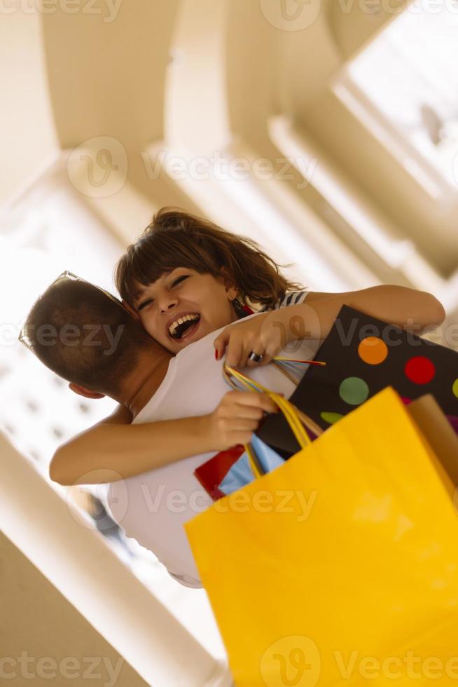 retrato de una alegre pareja joven caucásica hombre y mujer sosteniendo muchas bolsas de papel después de ir de compras mientras camina y habla en la calle. feliz pareja familiar con paquetes al aire libre. concepto de compra foto