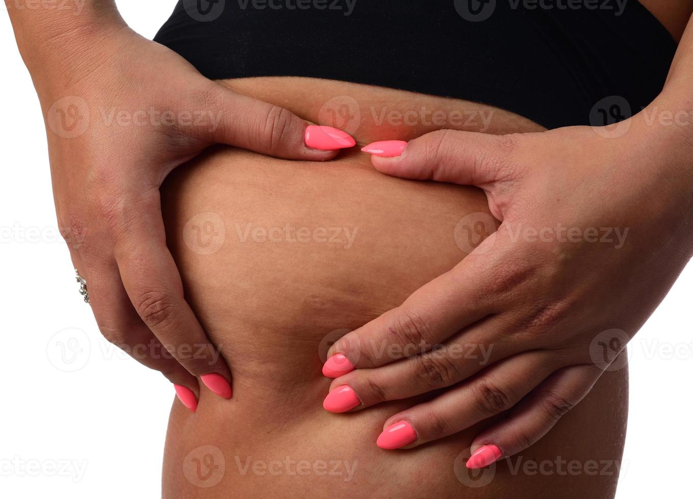 mujer gorda pellizcando su grasa en sus caderas, aislada sobre fondo blanco. foto