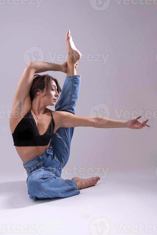 retrato de una hermosa joven con un cuerpo atlético y flexible haciendo estiramientos de piernas. aislado foto