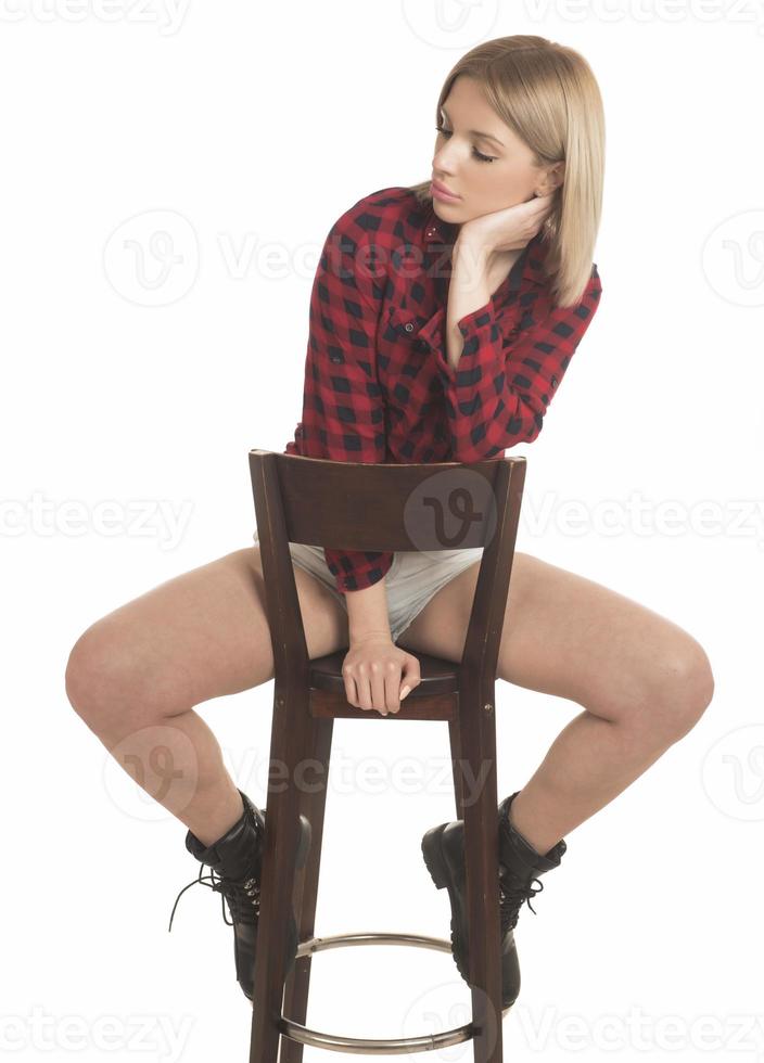 Smiling young woman sitting on stool. Isolated studio portrait on white back. photo