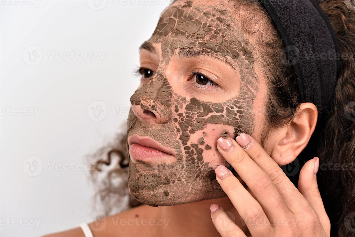 Beautiful woman removing clay facial mask from her face photo