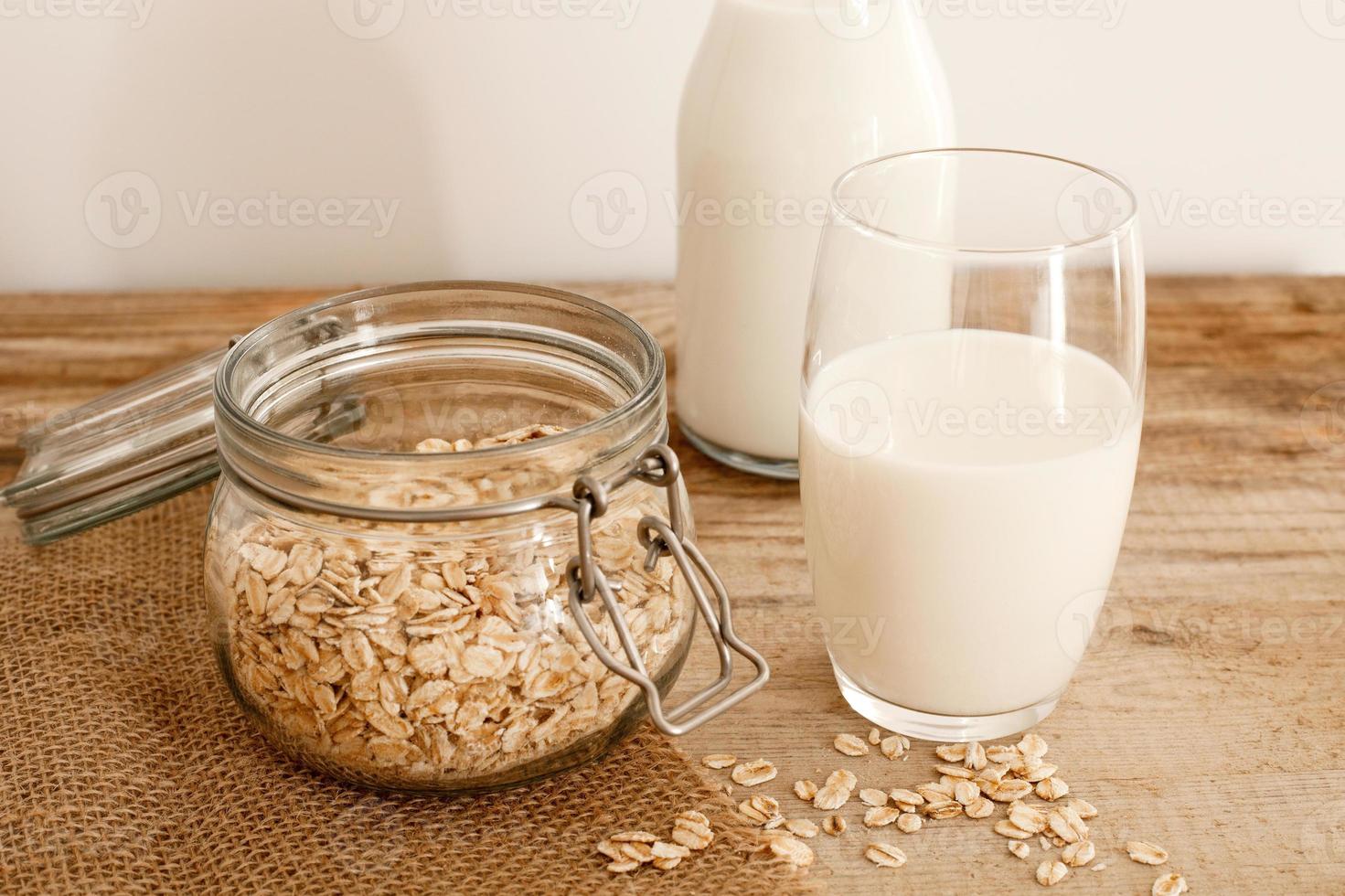 Fresh oat milk in glass bottle, vegan non dairy healthy drink. Wooden table, close-up. Alternative product, lactose free, natural ingredients. Healthcare, lactose intolerance. photo