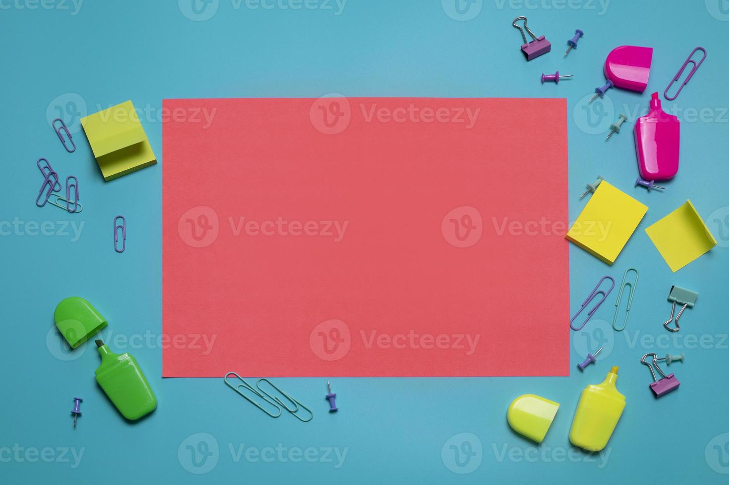 Stationery items on the blue background with free space for text. Creative, colorful background with scool or office supplies. Flatlay with copy space, top view. Markers, paper clips, sticky notes. photo