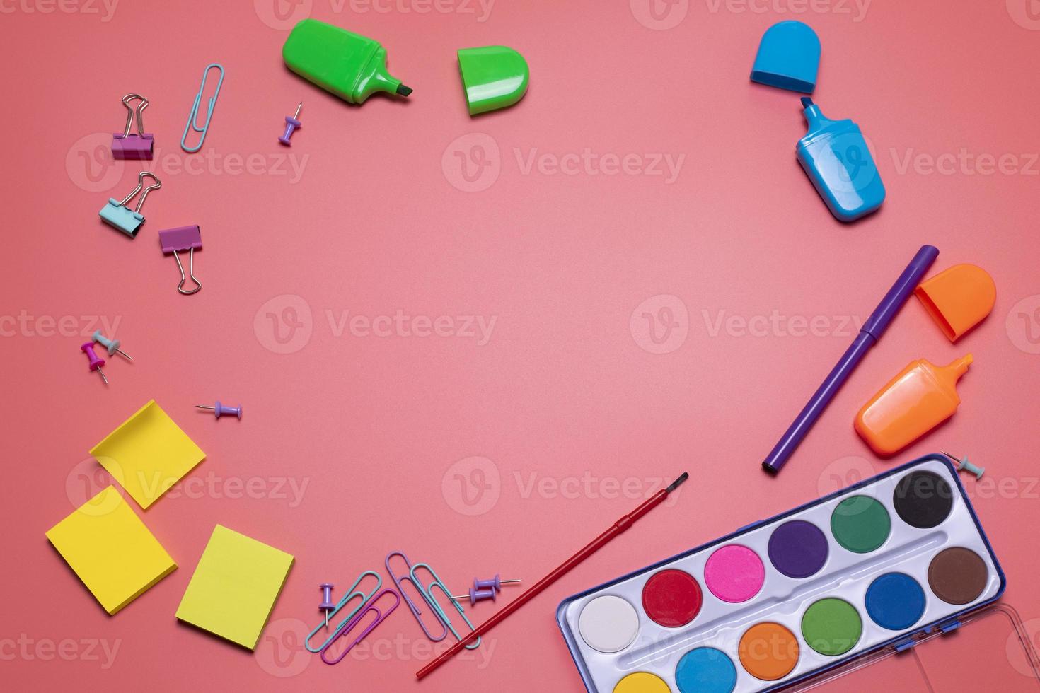 Stationery items on the pink background with free space for text. Creative, colorful background with scool supplies. Flatlay with copy space, top view. Markers, paper clips, sticky notes, watercolor. photo
