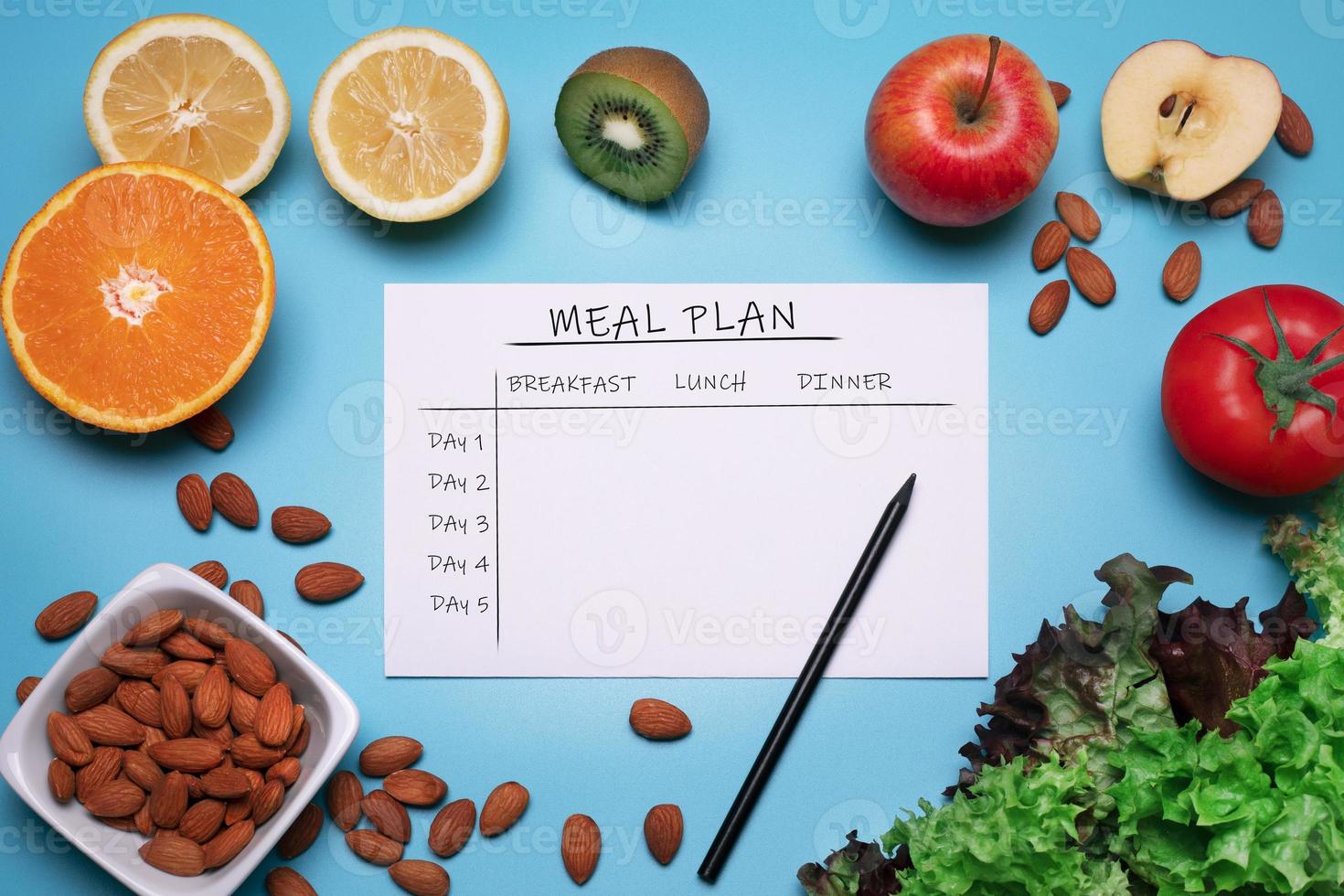 control de calorías, plan de comidas, dieta y concepto de pérdida de peso. vista superior del plan de comidas. endecha plana con varias frutas, verduras y nueces en el fondo azul foto