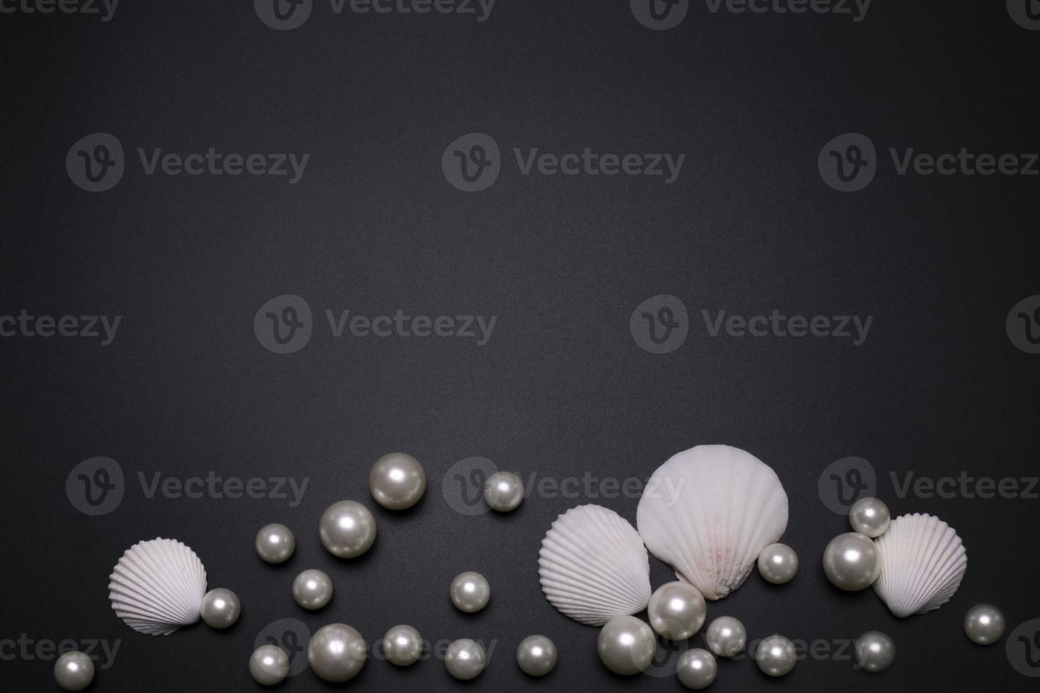 Sea shells and pearls on the black background, with free space for text. photo