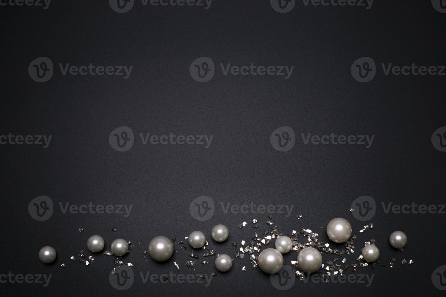 Glitter and pearls on the black background, with free space for text. photo