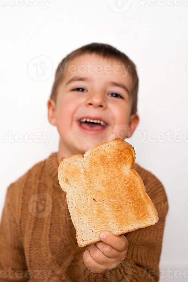 Children and gluten. Preschool boy with toasted bread. Gluten intolerance by kids. Copy space on bread for text or symbol. photo