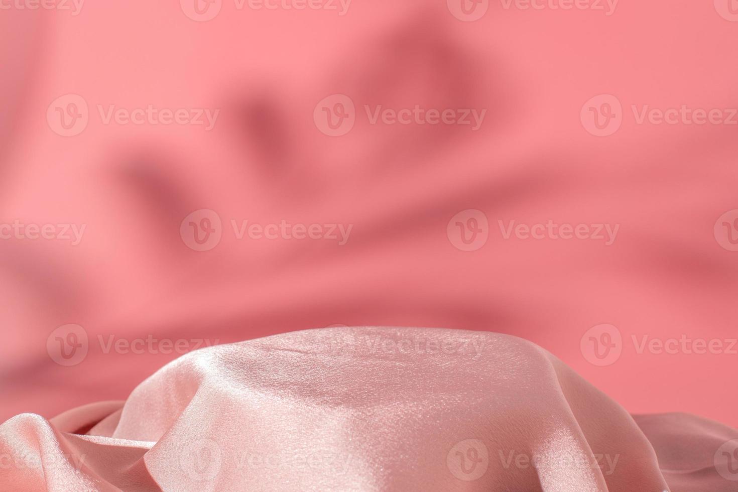 Pink silk podium on the pink background with shadow of tropical plant. Elegant scene. Podium for product, cosmetic presentation. Creative mock up. Pedestal or platform for beauty products. photo