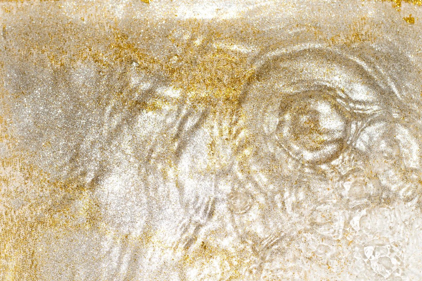Golden and silver sparkles in water. Glitter and liquid texture. Abstract background with golden an silver particles. Shining celebration background. Festive backdrop for your projects. photo