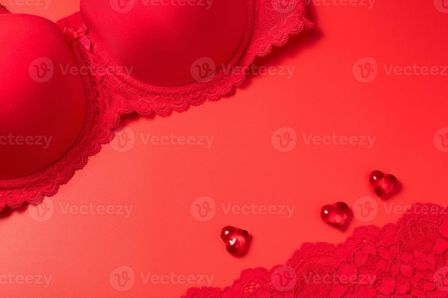 Red Valentine's Day background with beautiful female lacy panties, bra and hearts. Sexy underwear. Free space for text, copy space. Postcard, greeting card design. Love, celebration concept. photo