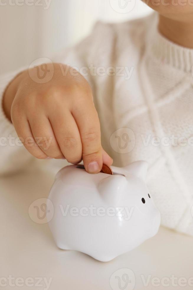 niño pequeño poniendo monedas de dinero en la alcancía para ahorrar dinero. riqueza, presupuesto, inversión, concepto de finanzas. niño y caja de dinero, alcancía. foto