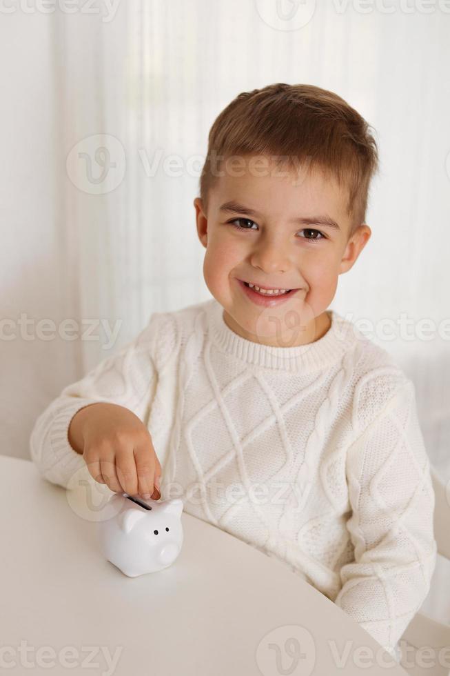 Little boy putting money coin into piggy bank for saving money. Wealth, budget, investment, finance concept. Child and money box, piggybank. photo