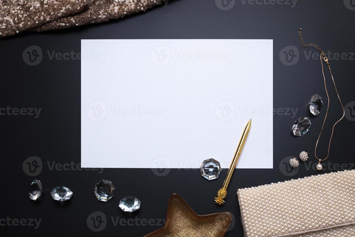 Elegant background, template for text or logo. White, empty paper sheet, jewellery and other accessories on the black background. Free space, copy space. Fashion, beauty backdrop. photo