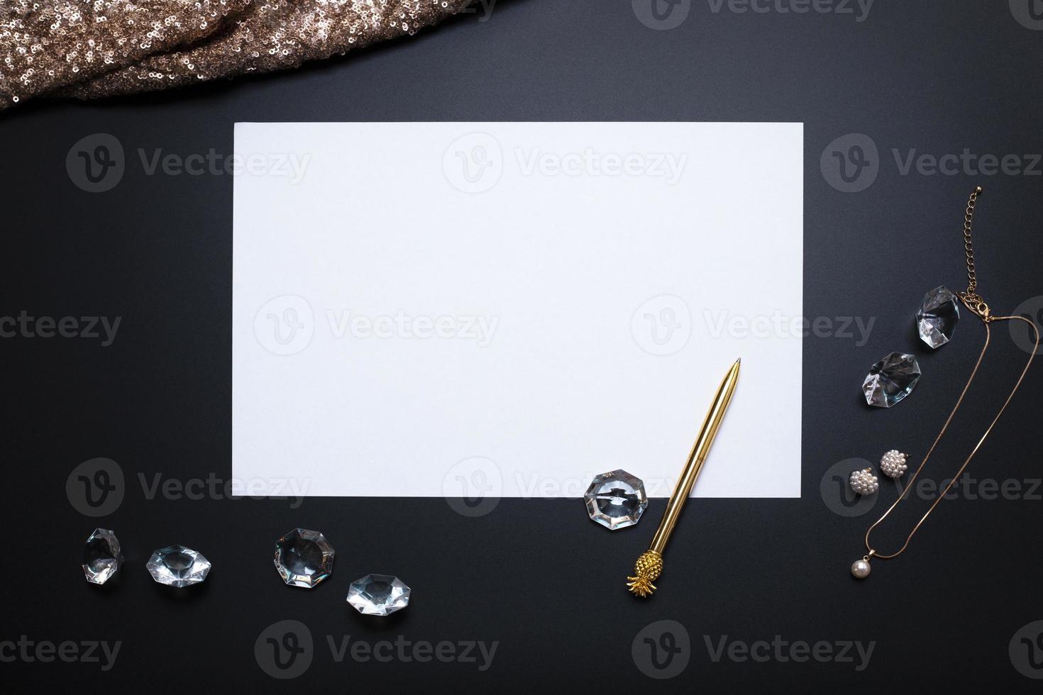 Elegant background, template for text or logo. White, empty paper sheet, jewellery and other accessories on the black background. Free space, copy space. Fashion, beauty backdrop. photo