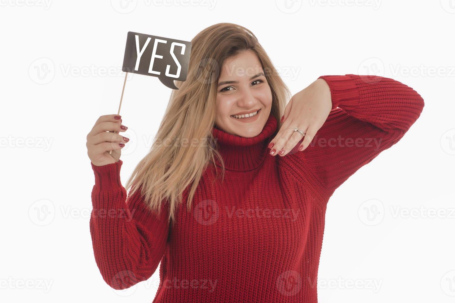 mujer sosteniendo un anillo de compromiso y un cartel diciendo que sí foto