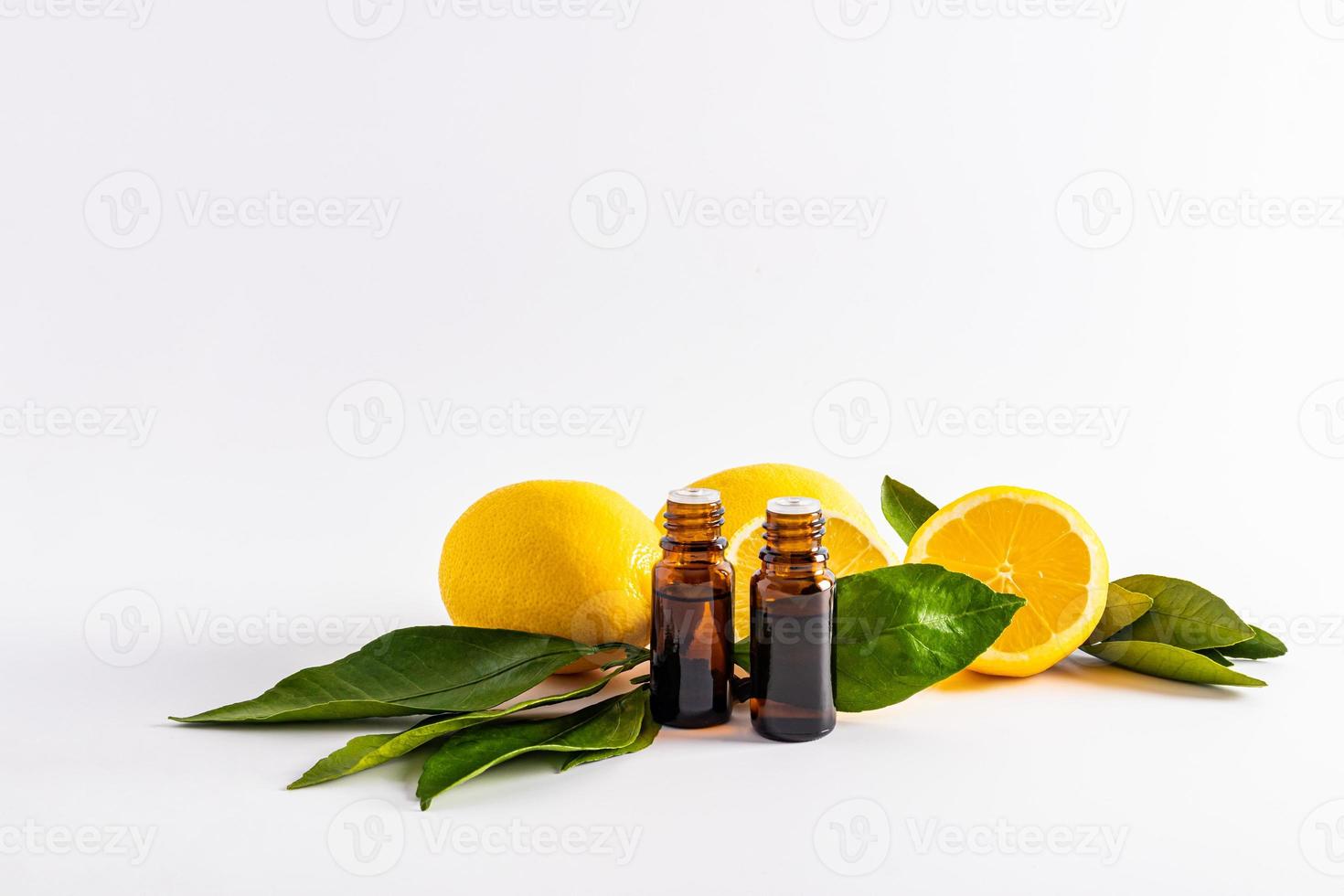 two bottles of dark glass on the background of ripe lemons and slices. lemon essential oil, lemon juice extracts, lemon essence for home use. photo