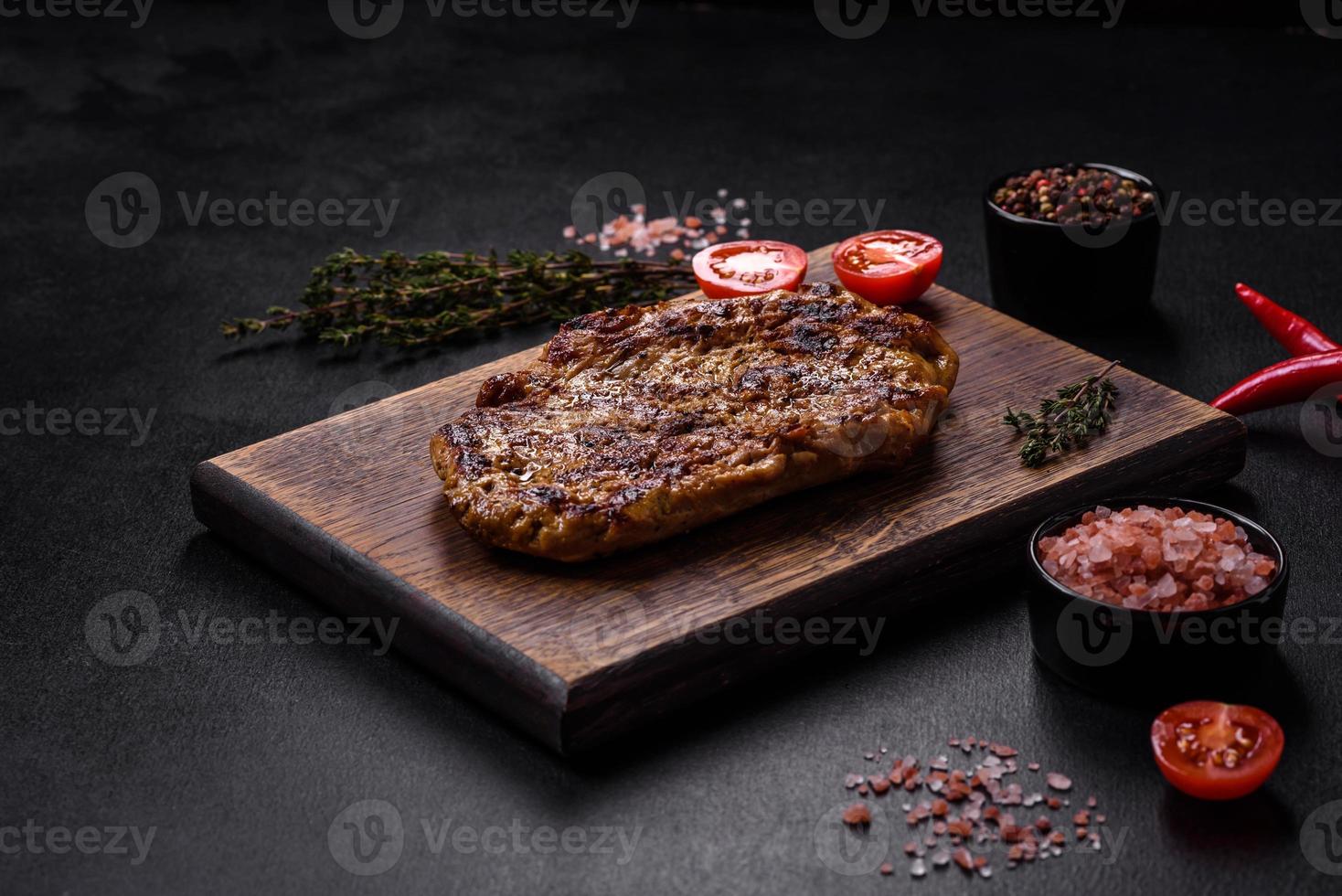 Delicious juicy grilled pork steak with spices and herbs photo