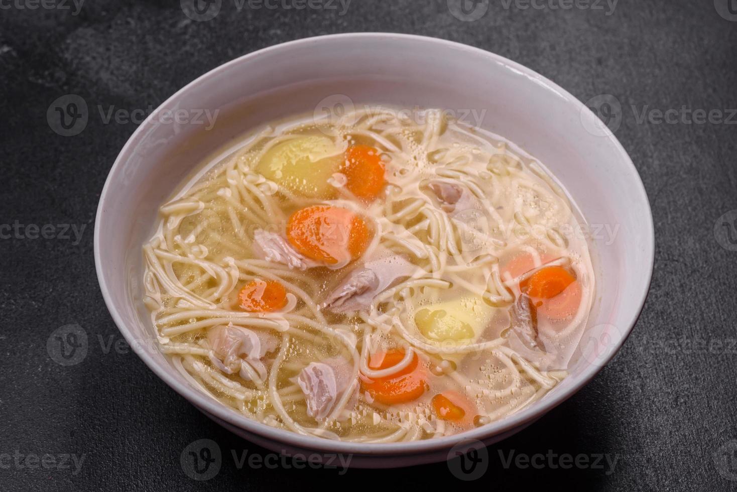 Delicious soup with noodles, chicken and carrots with spices and herbs photo