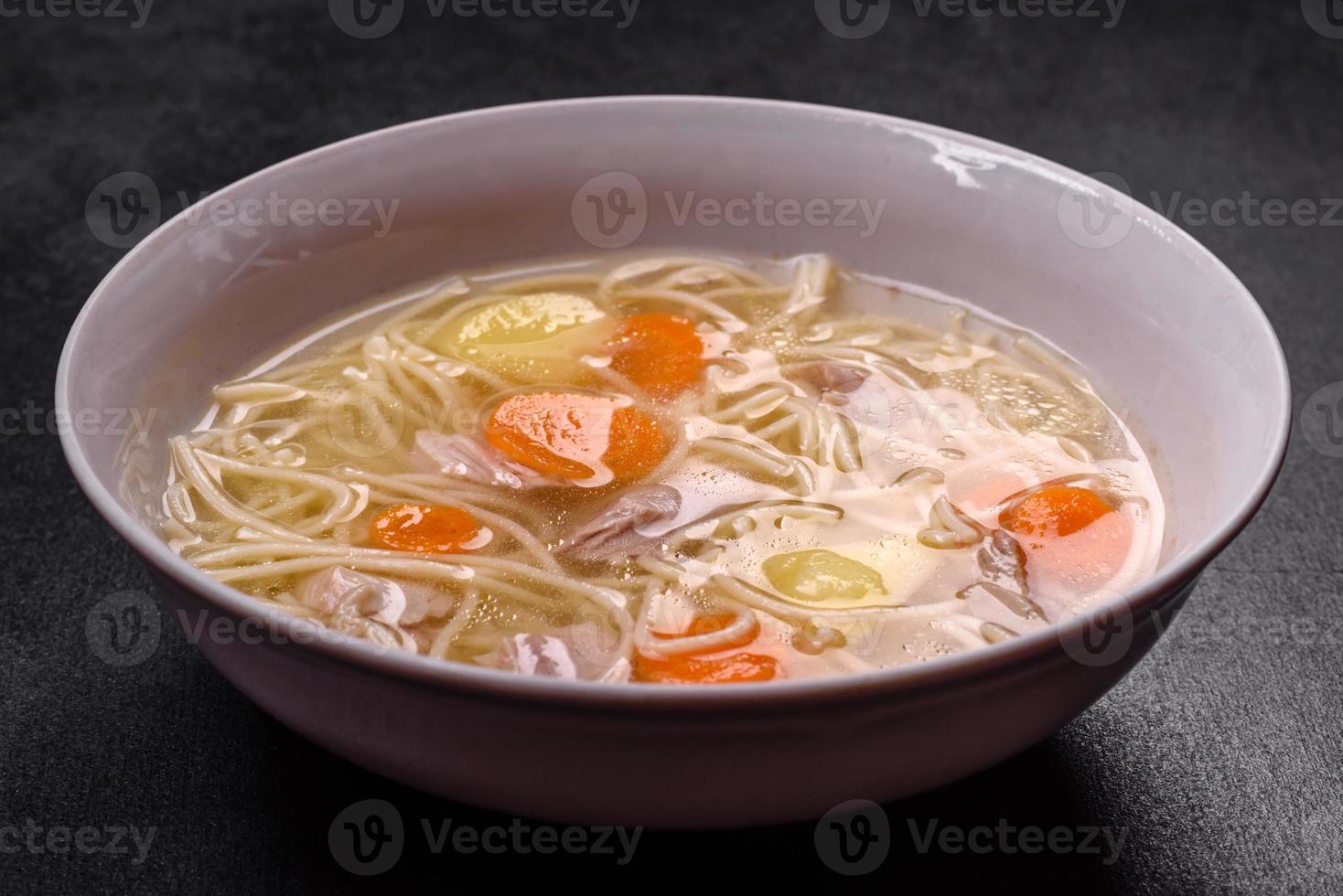 Delicious soup with noodles, chicken and carrots with spices and herbs photo