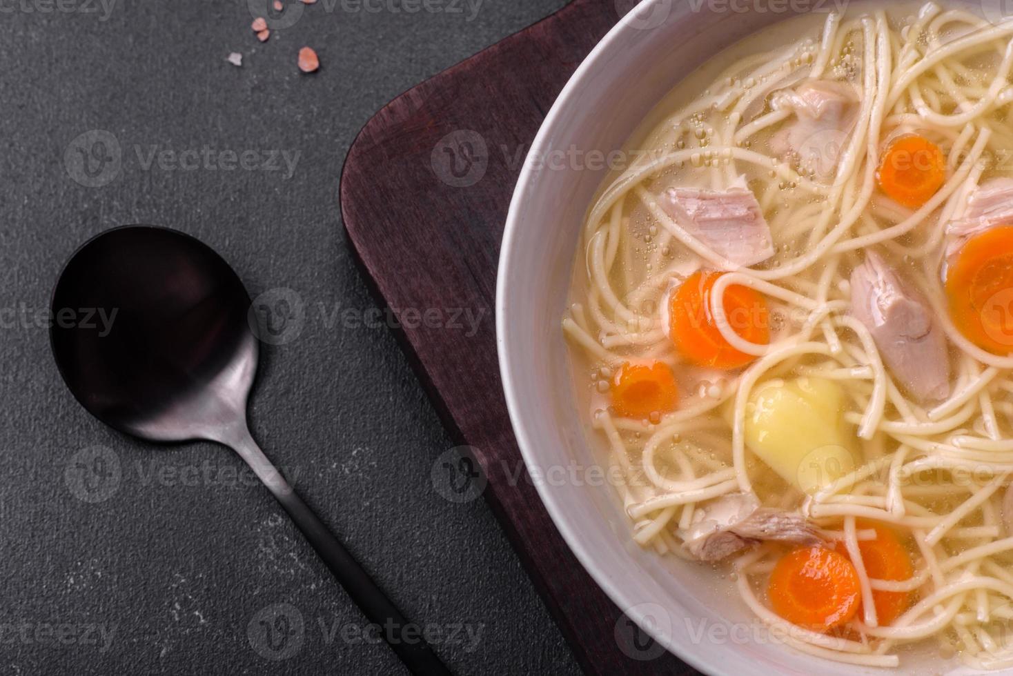 Delicious soup with noodles, chicken and carrots with spices and herbs photo