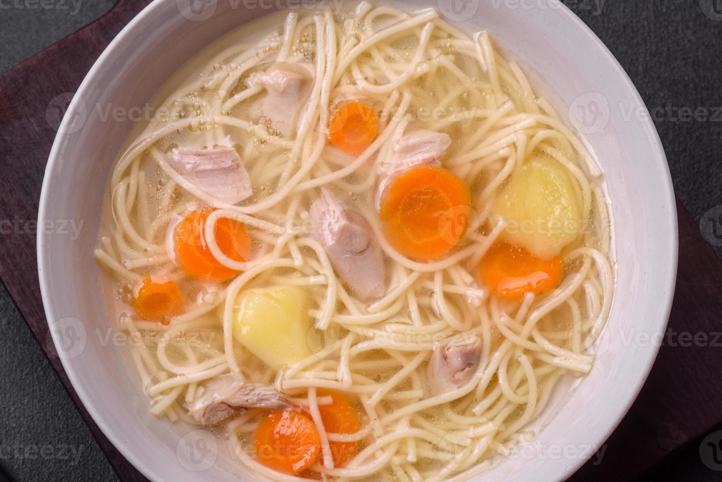 Delicious soup with noodles, chicken and carrots with spices and herbs photo