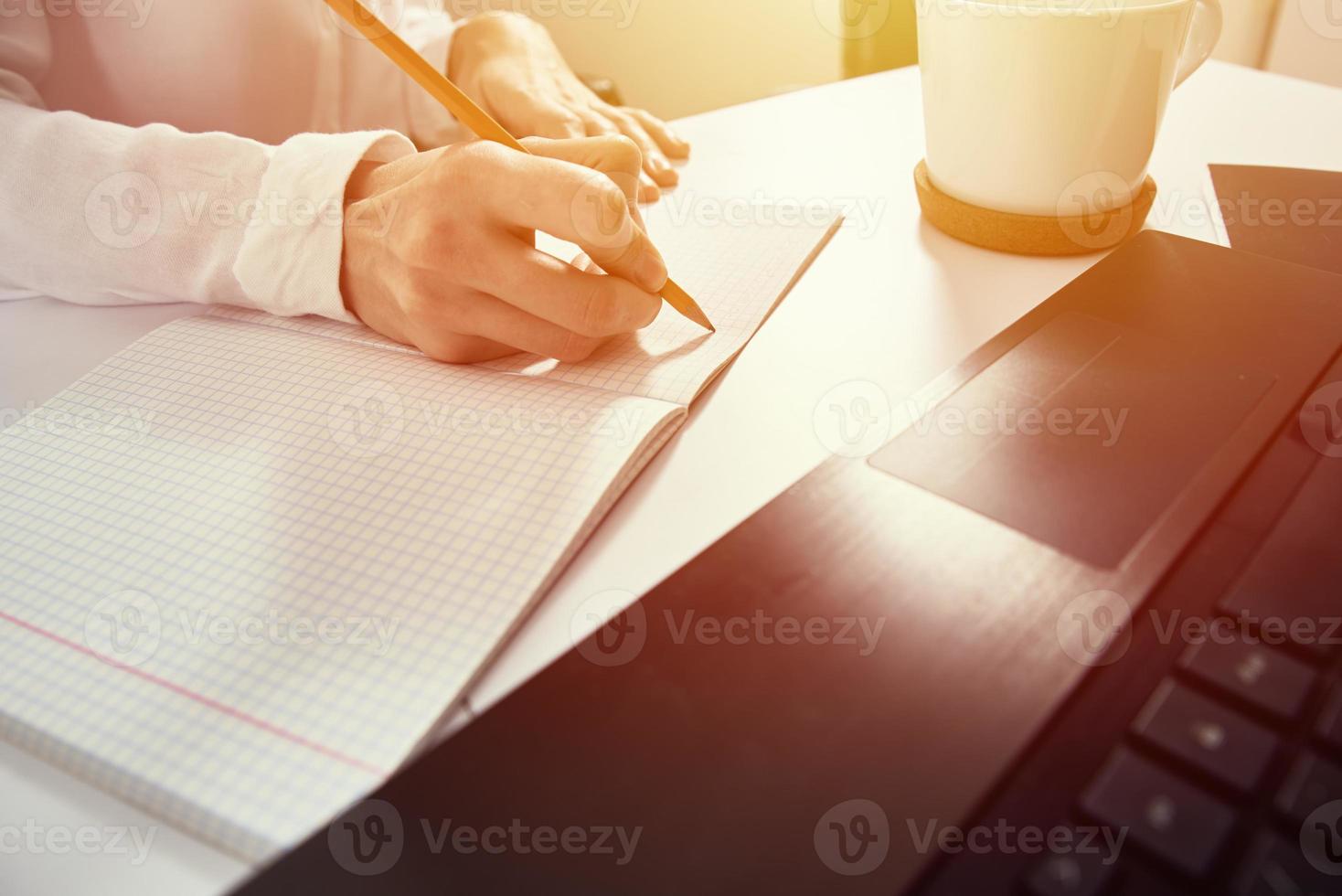 Woman makes notes in notebook and using laptop for study photo