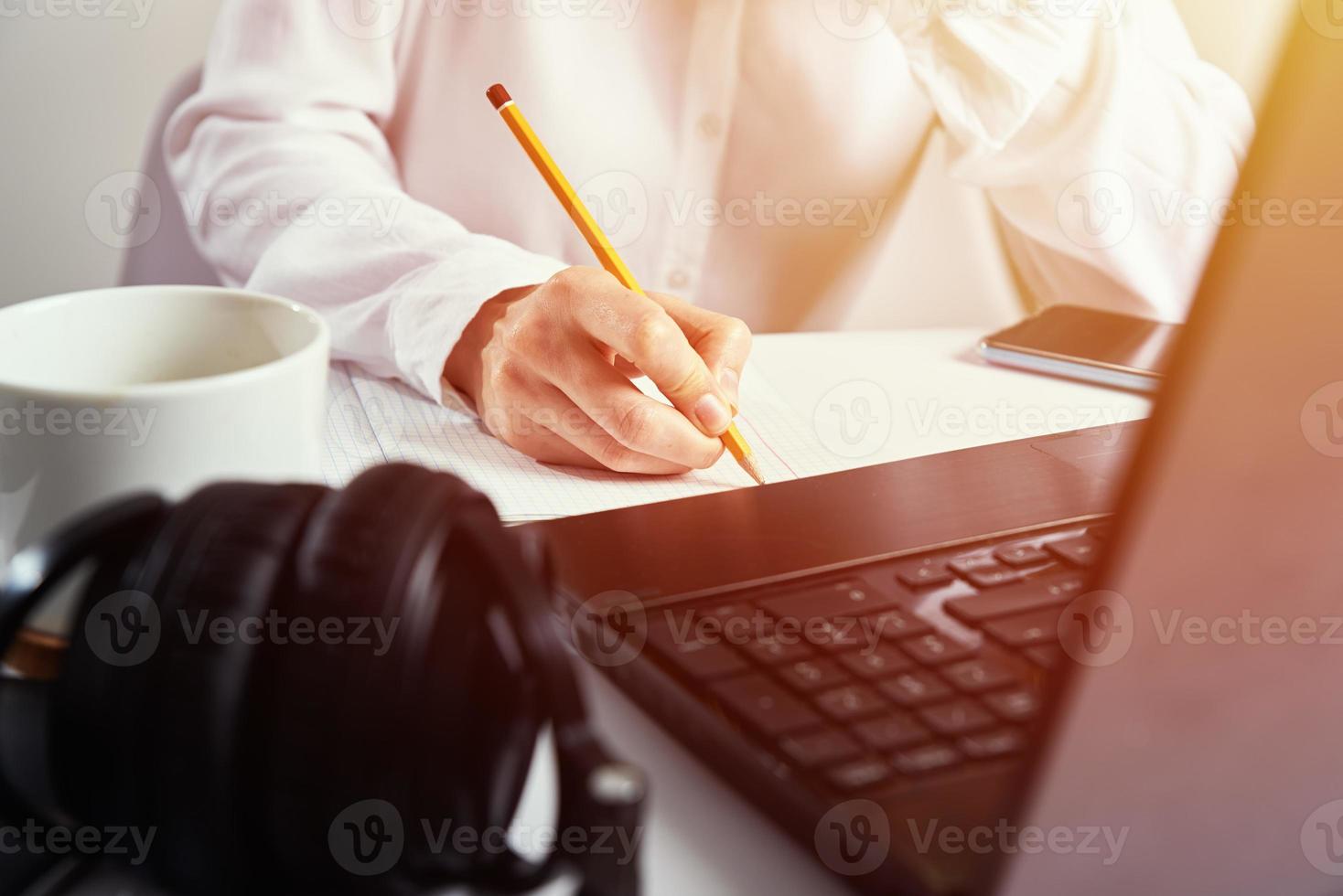 Woman makes notes in notebook and using laptop for study photo