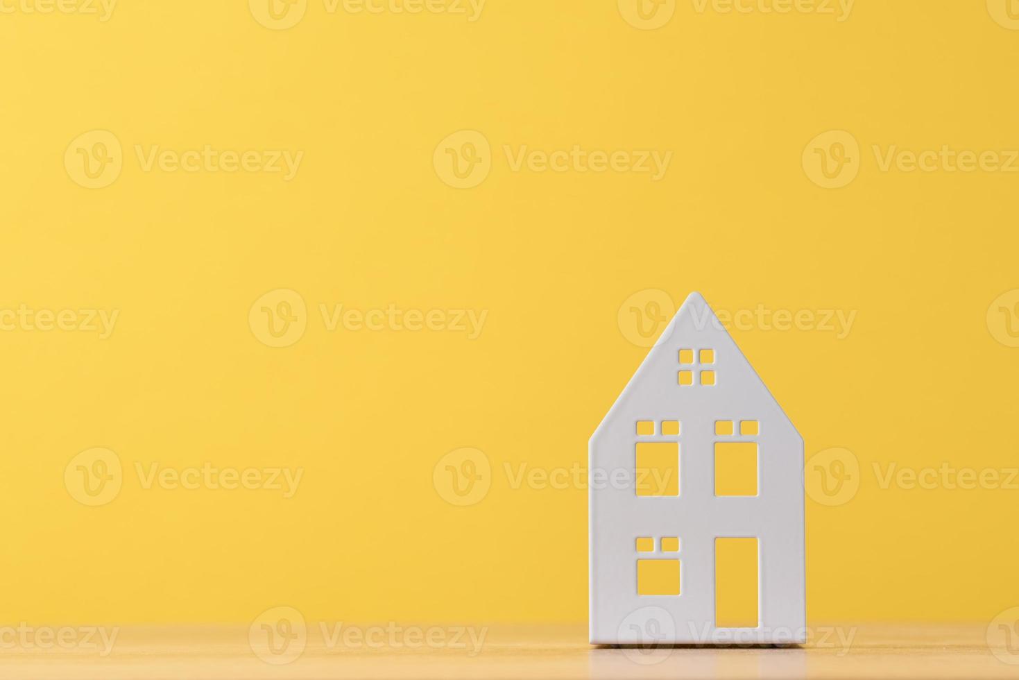 Figure of toy house on a yellow background with copy space photo