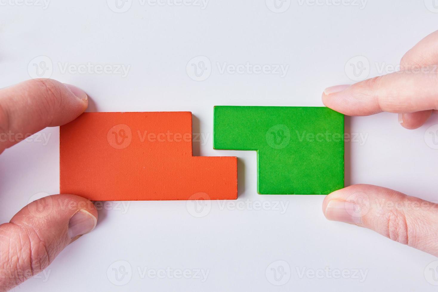 Dos manos conectan piezas de rompecabezas sobre fondo blanco. foto