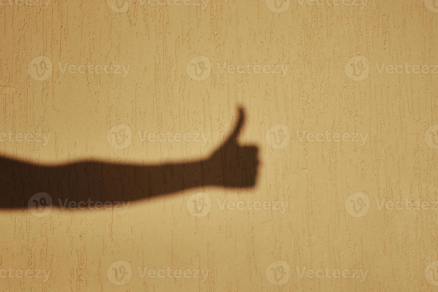 Thumb up gesture shadow on wall photo