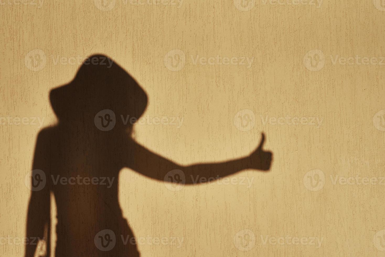 Shadow of woman shows thumb up gesture on the wall photo