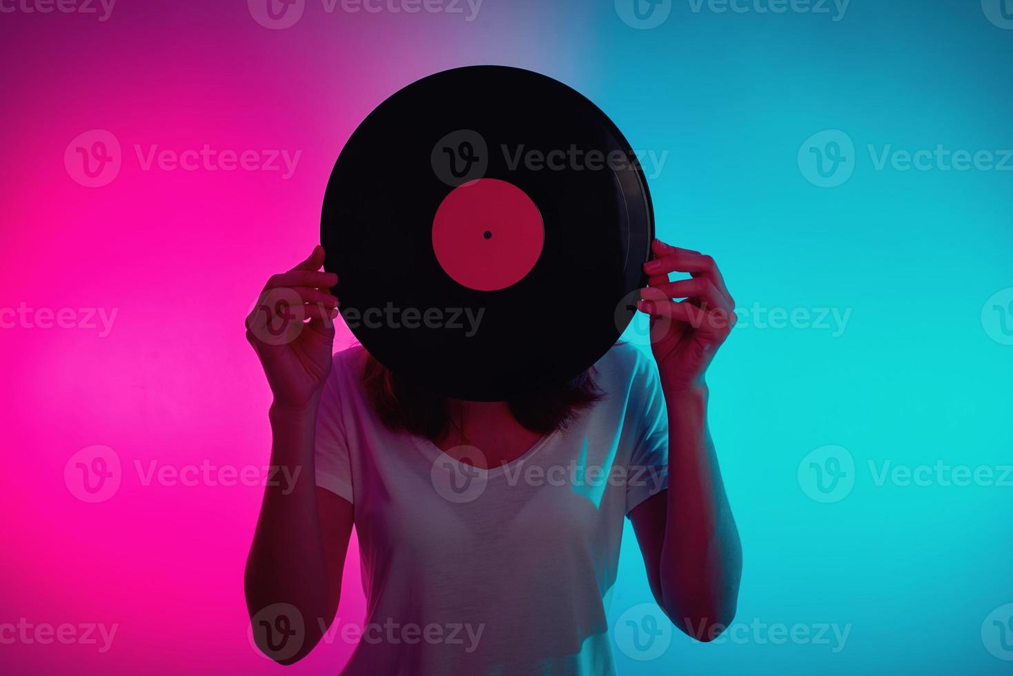 Woman hold retro vinyl disc with neon light photo