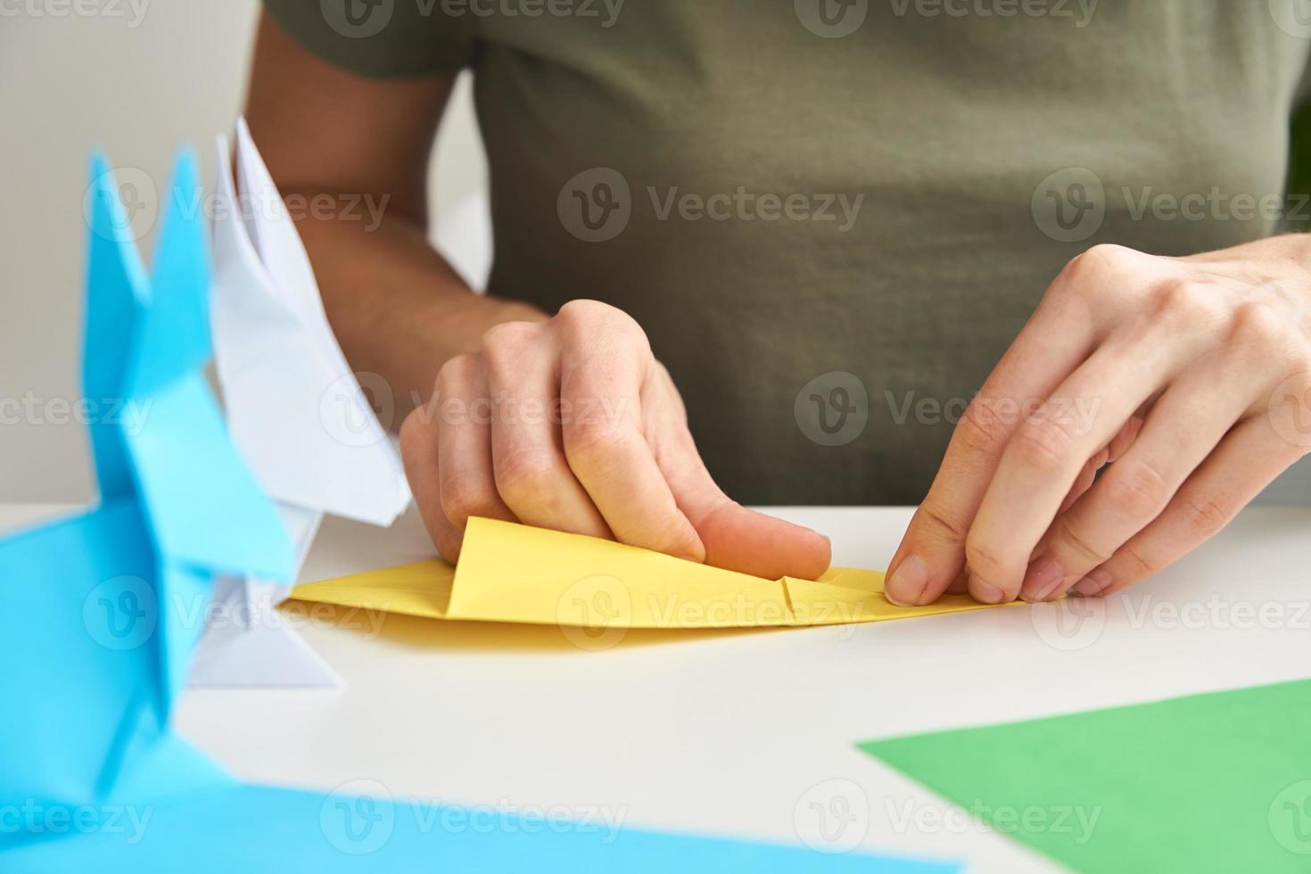 concepto de bricolaje. mujer hace origami conejo de pascua con papel de color. lecciones de origami foto