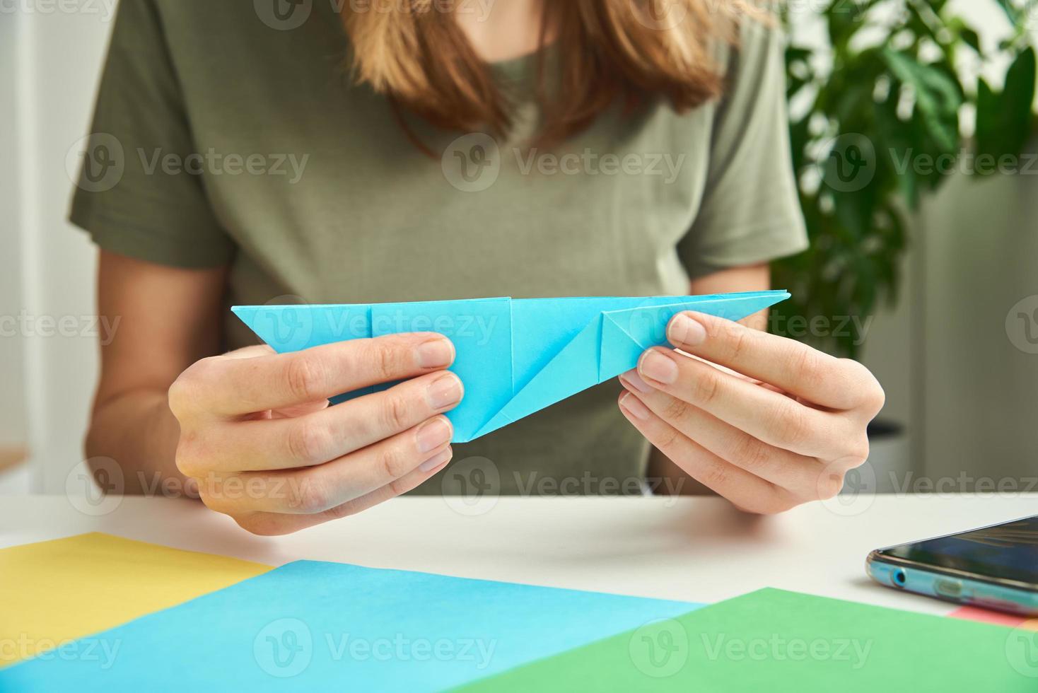 DIY concept. Woman make origami easter rabbit from color paper. Origami lessons photo