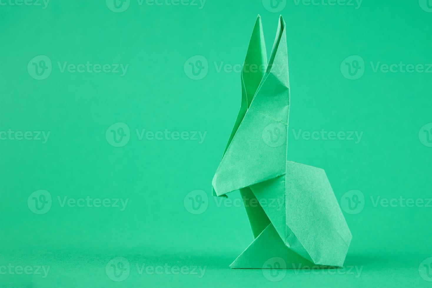Paper origami Esater rabbit on a green background. Easter celebration concept photo