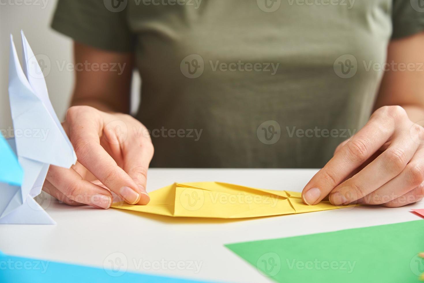 DIY concept. Woman make origami easter rabbit from color paper. Origami lessons photo