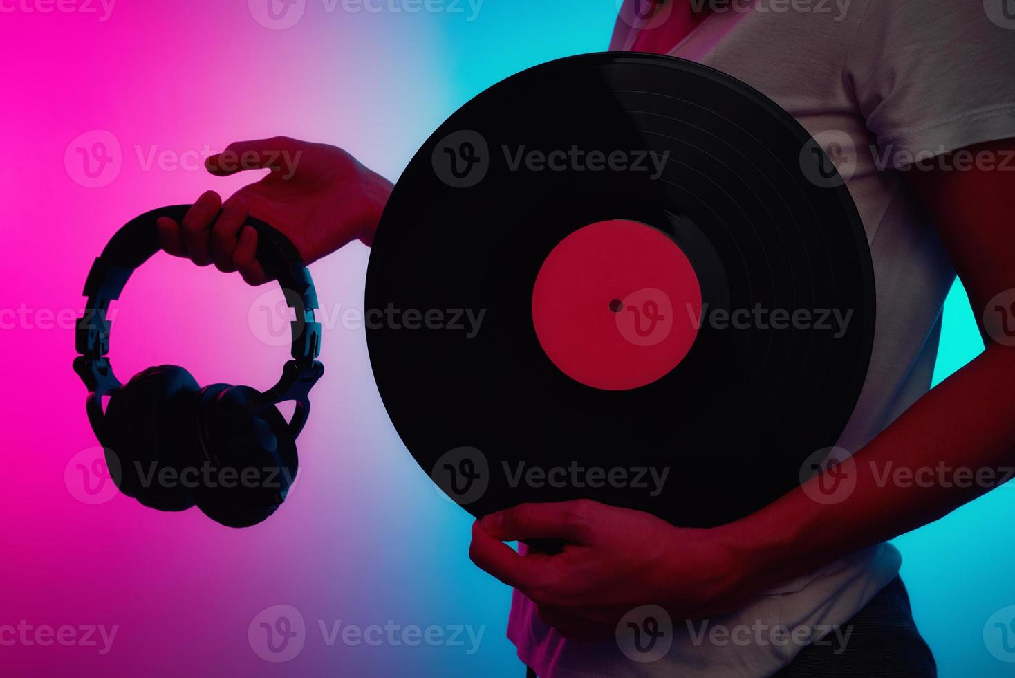 Woman hold retro vinyl disc and headphones with neon light photo