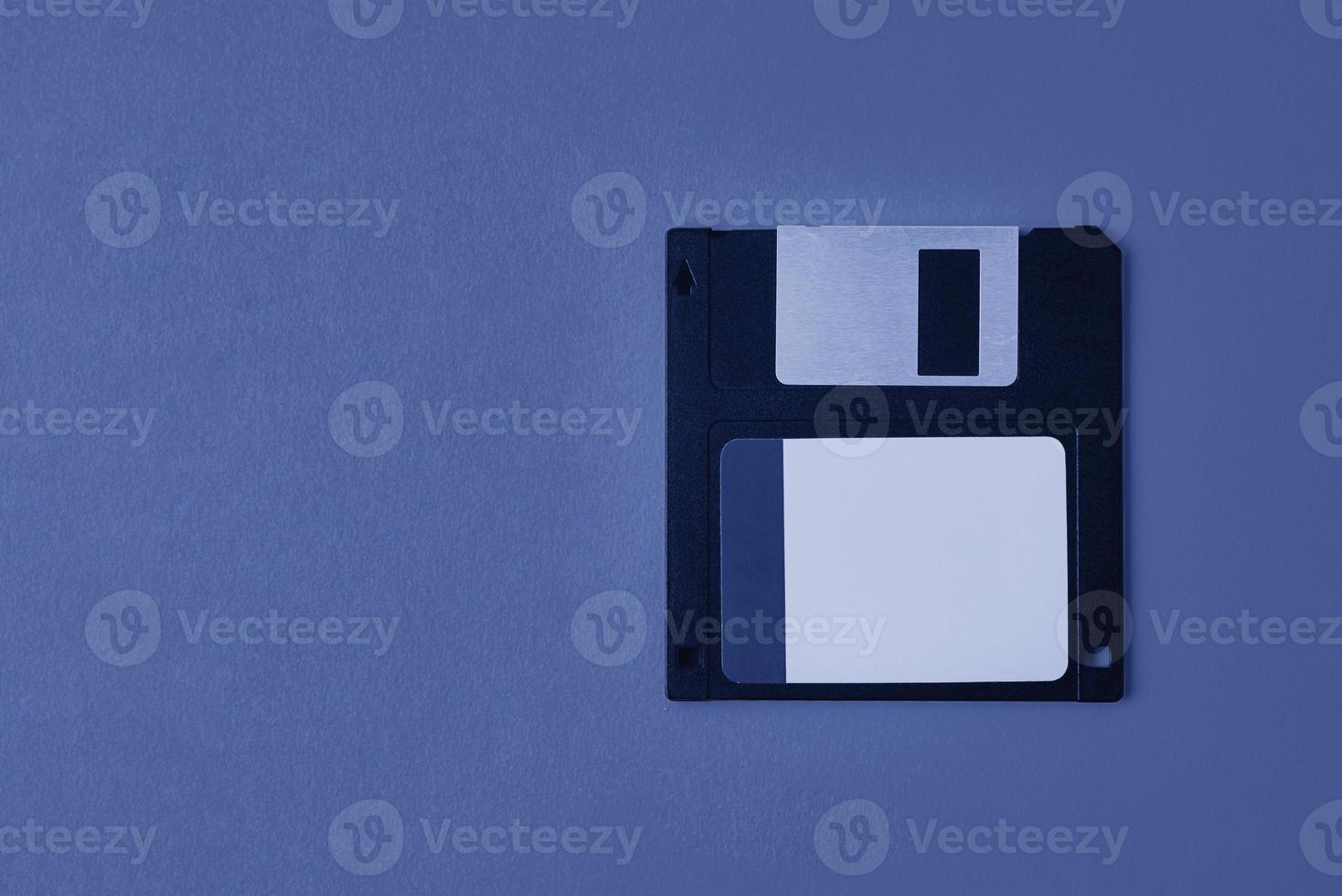 Black floppy diskette on blue background. Vintage computer diskette, closeup photo