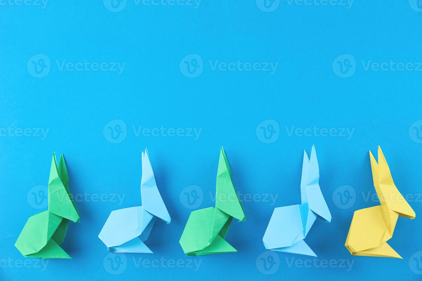 Paper colorful origami Esater rabbits on blue background photo