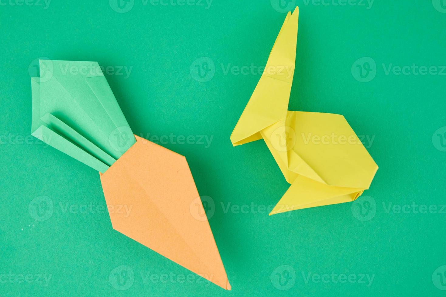 Paper origami rabbit and carrot on green background photo