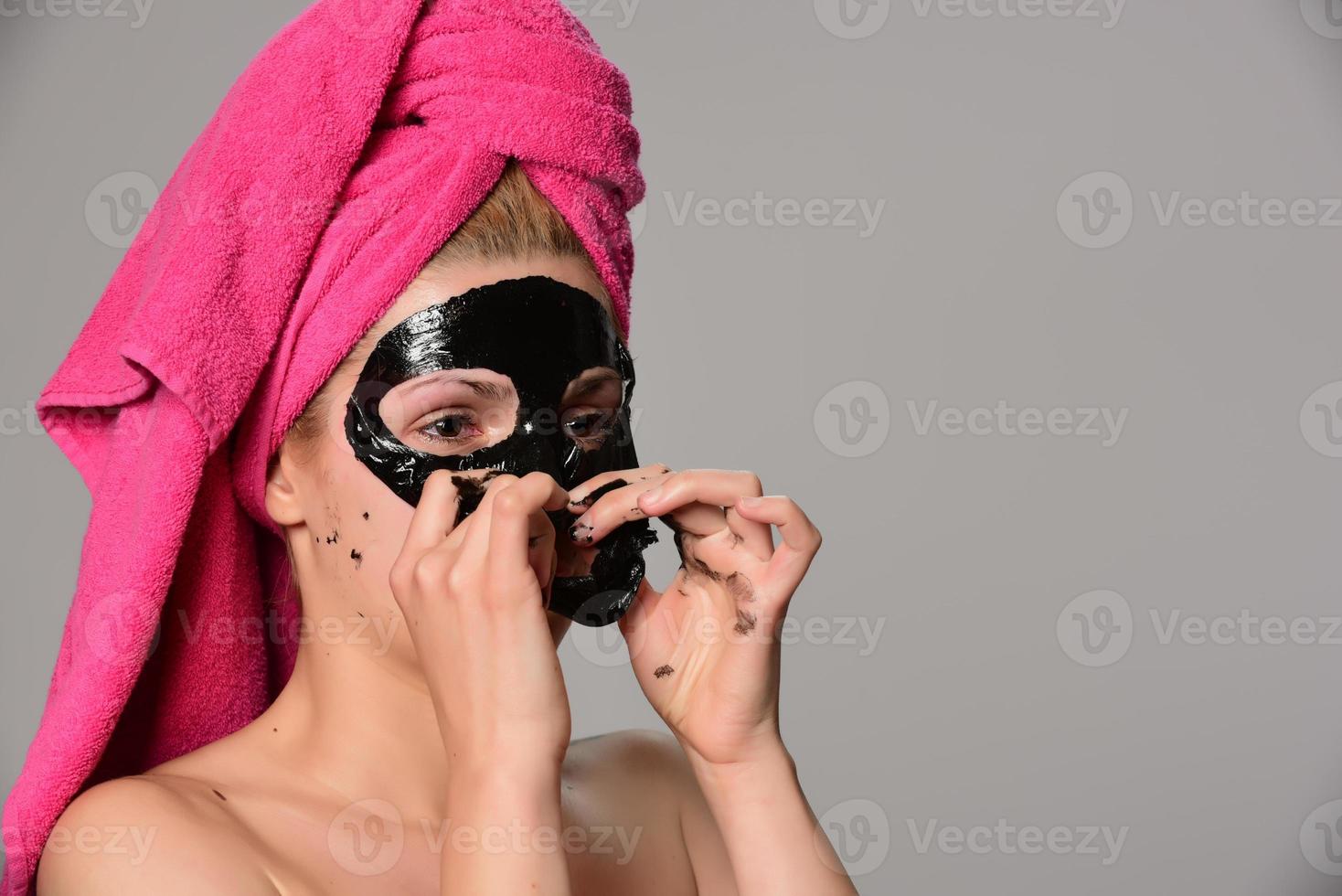 beautiful female model with black facial cosmetic mask. Isolated on gray background photo