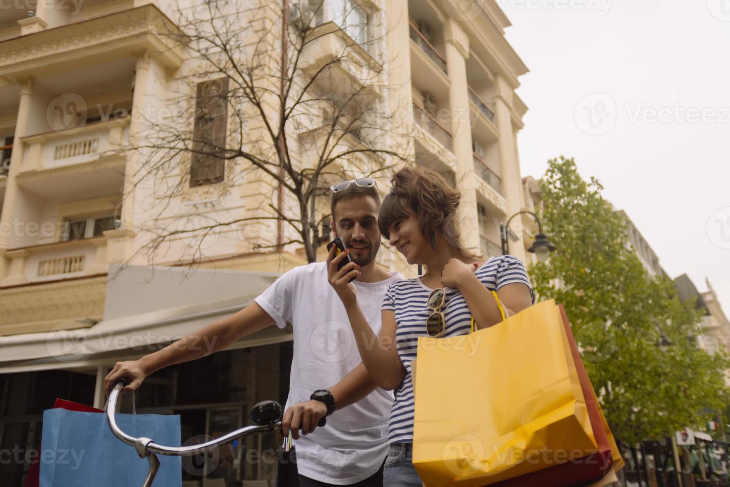 retrato de una alegre pareja joven caucásica hombre y mujer sosteniendo muchas bolsas de papel después de ir de compras mientras camina y habla en la calle. feliz pareja familiar con paquetes al aire libre. concepto de compra foto