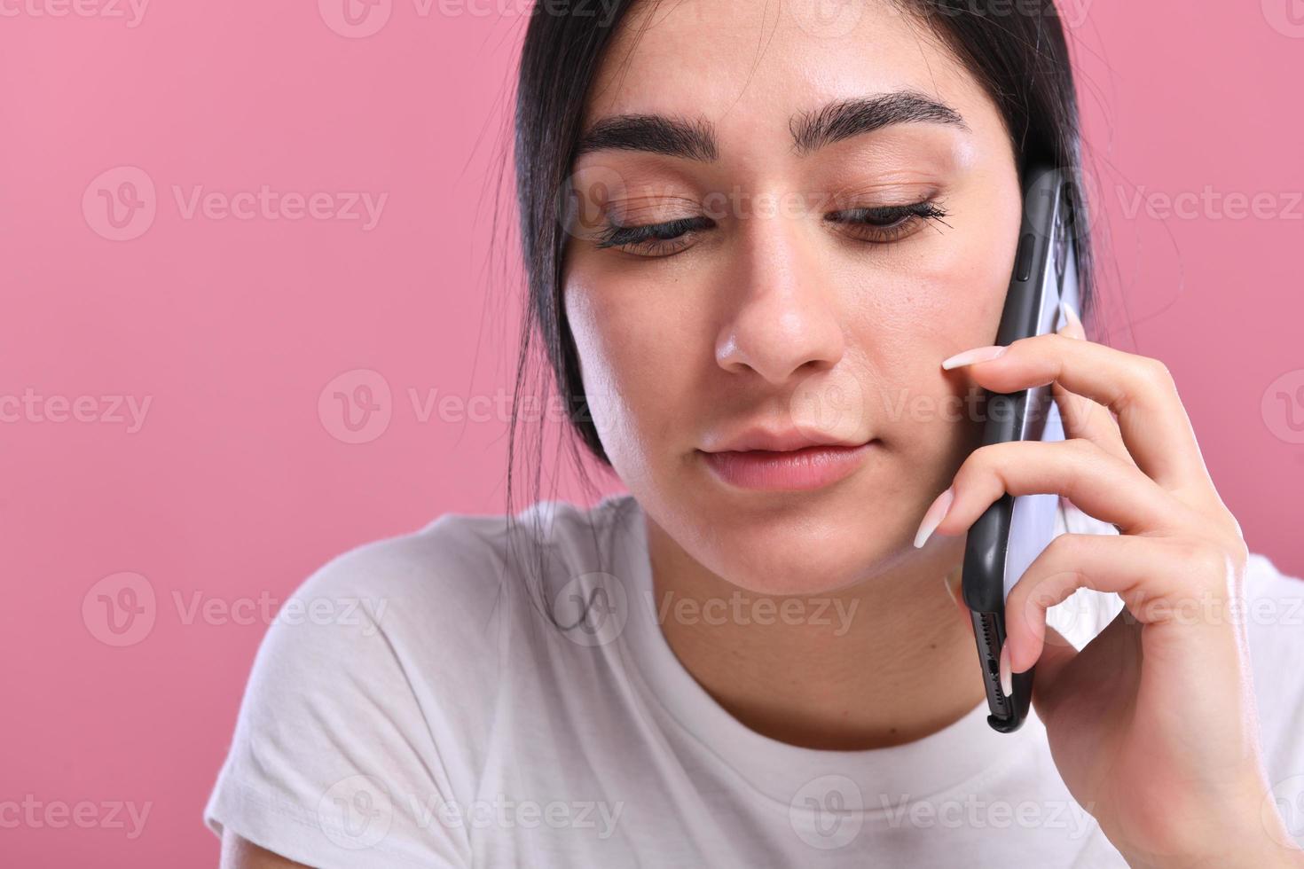 Portrait of a smiling young casual brunette woman talking on mobile phone photo