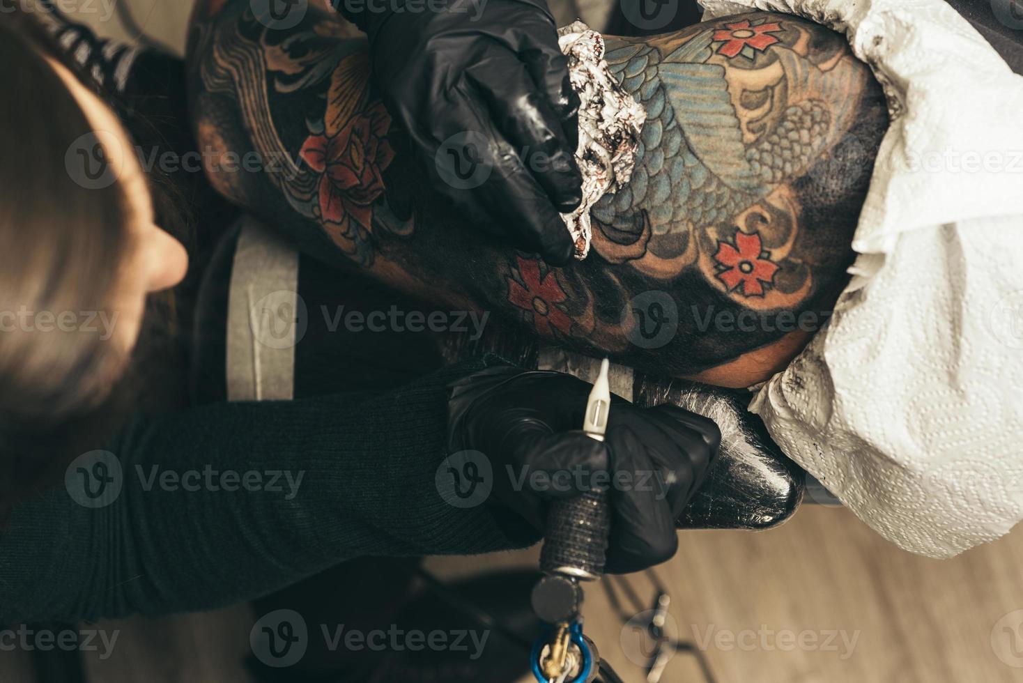 close up tattoo machine. Woman creating picture on hand with it in salon photo