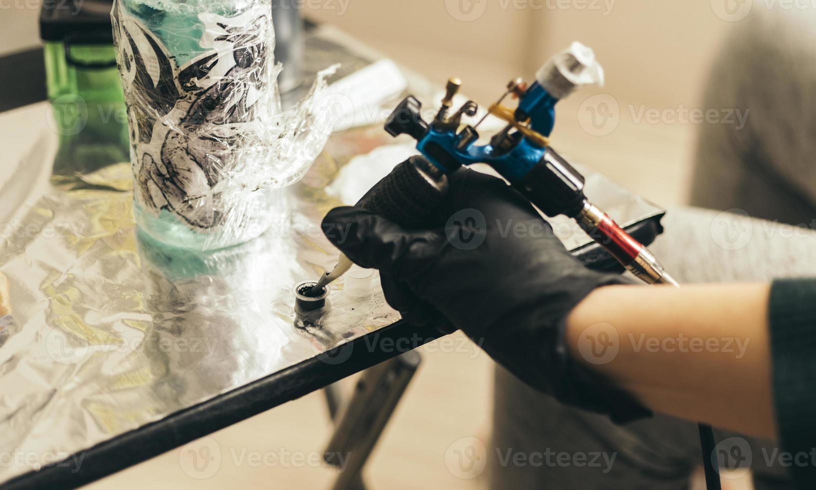 close up tattoo machine.  Woman creating picture on hand with it in salon photo