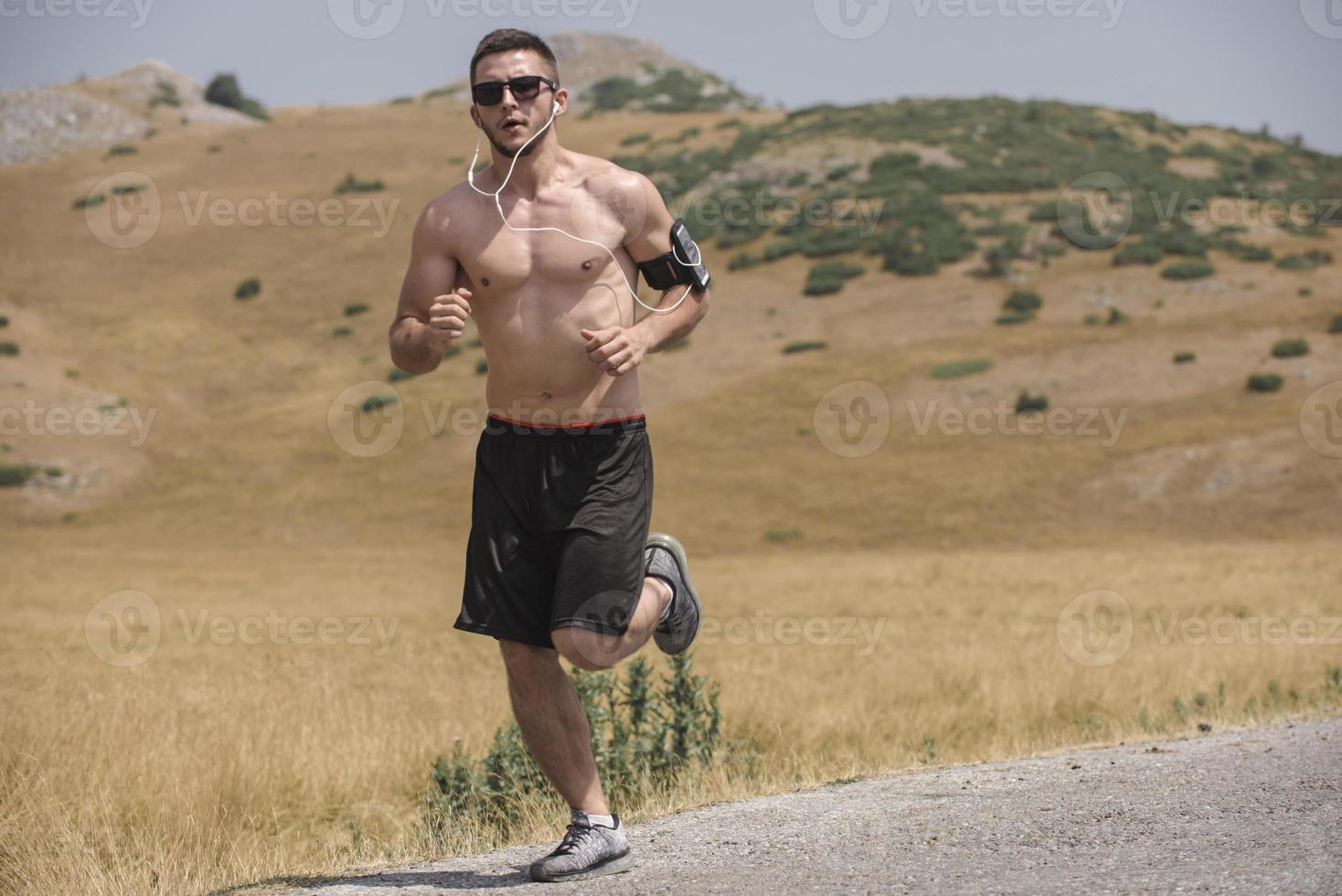 sporty man runner running on mountain plateau in summer photo