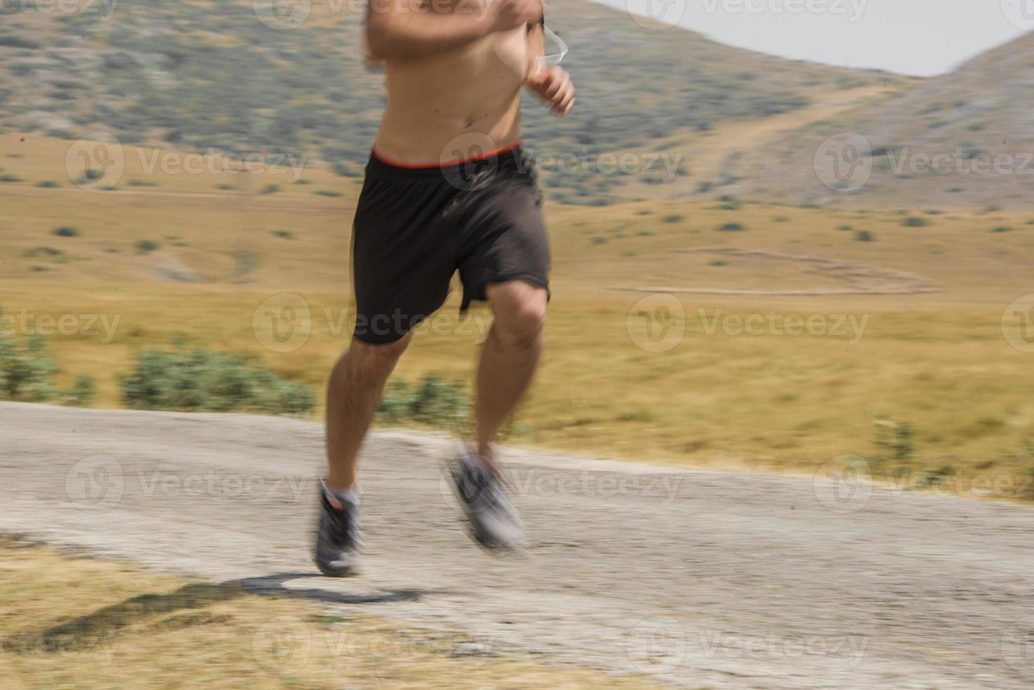sporty man runner running on mountain plateau in summer photo