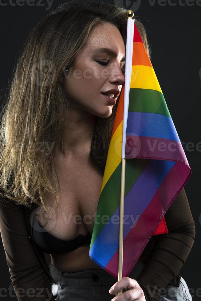 mujer lesbiana sosteniendo la bandera del arco iris aislada sobre fondo negro. símbolo internacional lgbt de la comunidad lesbiana, gay, bisexual y transgénero. foto